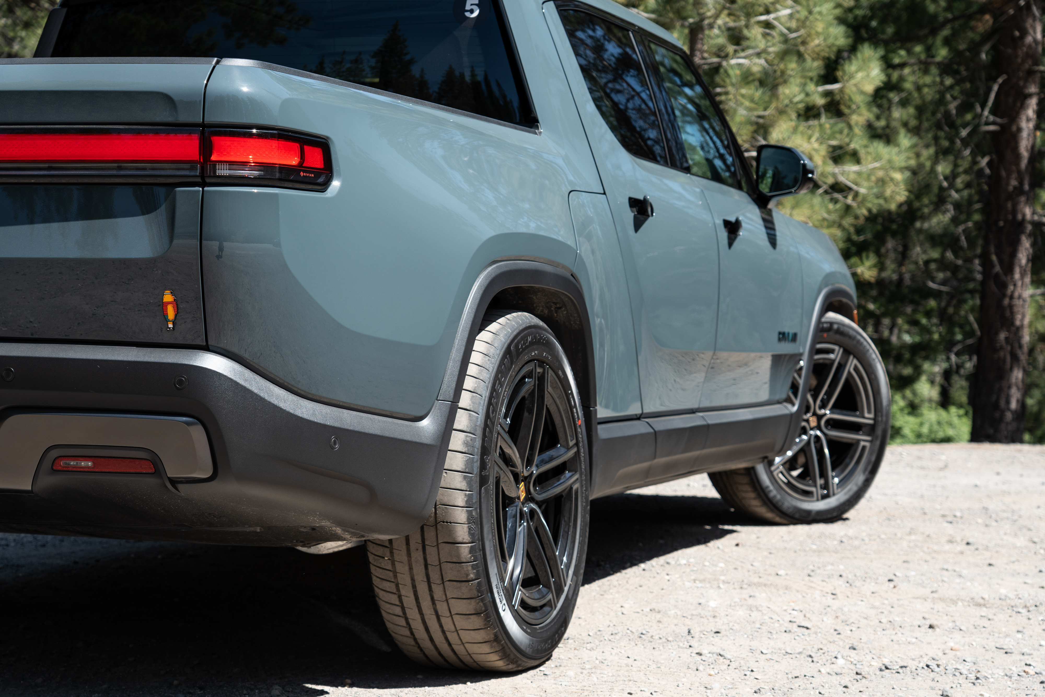 The side of a Rivian R1T, seen from the rear.