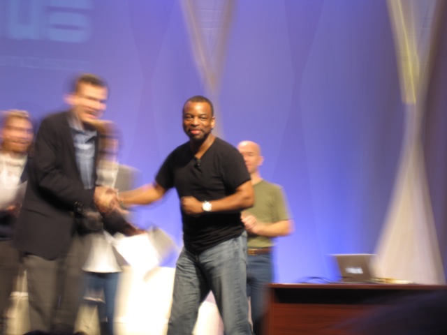 A blurry photo I took of Burton shaking Pogue's hand at the Macworld Expo in 2010, just after announcing that <em>Reading Rainbow</em> would be coming to the Internet