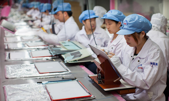 People in matching white uniforms work at a long table.