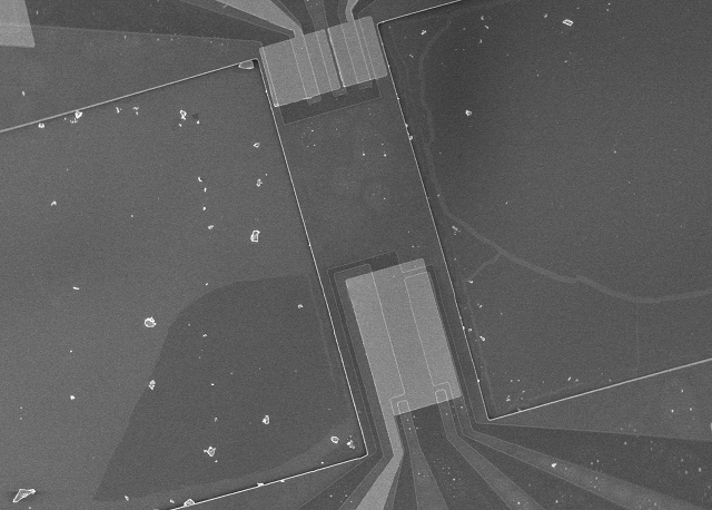 Electron micrograph of the phonon cavity; the lighter gray is the gold electrodes, while the rectangular bar is the resonating wafer..