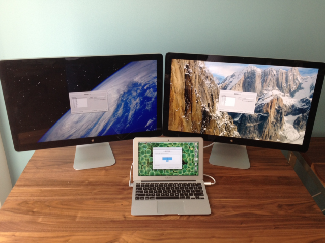 The 2012 MacBook Air is dwarfed by the two external Thunderbolt Displays it can drive.