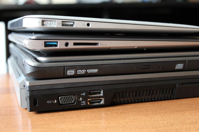 The UX31A, second from the top of the stack, compared to the MacBook Air (top of the stack), the Acer Aspire Timeline Ultra M5 gaming Ultrabook (second from bottom), and my chunky old Dell Latitude E6410 (bottom).