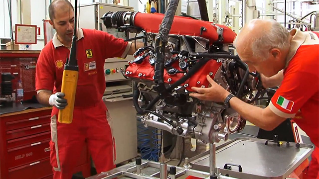 Workers assemble the engine for a Ferrari 458 Italia, which uses direct injection.