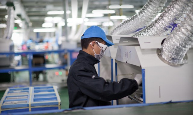 A worker using a laser etching machine wears a protective mask and safety goggles at a facility in Chengdu, China.