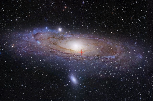 The red crosshairs mark the location of a microquasar in M31, the Andromeda Galaxy. A microquasar consists of powerful light emissions from matter surrounding a stellar mass black hole.