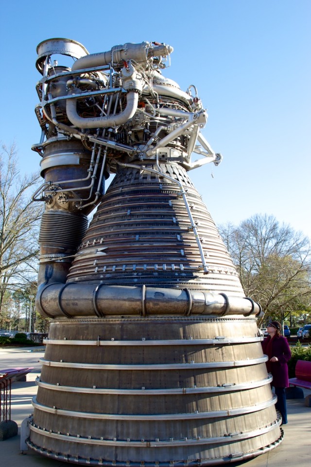 An F-1 engine (with nozzle extension) on display at MSFC. Author's wife standing next to engine for scale.