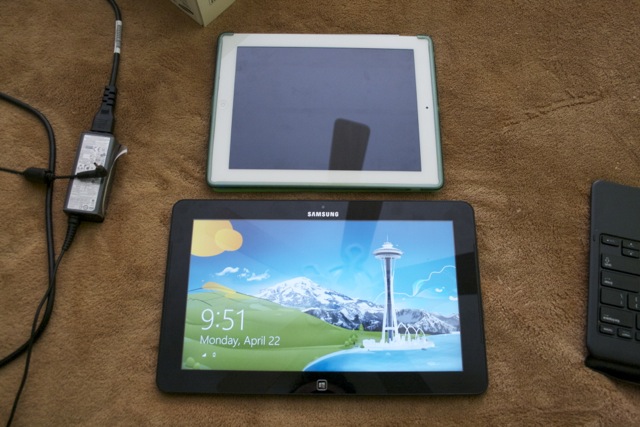 A size comparison between the Ativ Tab 7 in tablet mode (alongside its power supply) and an iPad 2. 