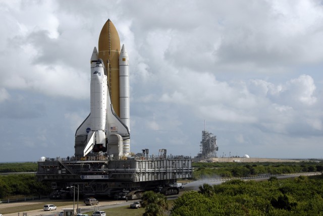 Under troubled skies, <em>Atlantis</em> makes its way out to the pad atop one of the Crawler-Transporters to embark on STS-129.