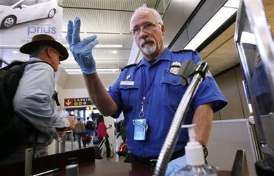 A TSA agent signals to a passenger at a security check point. 