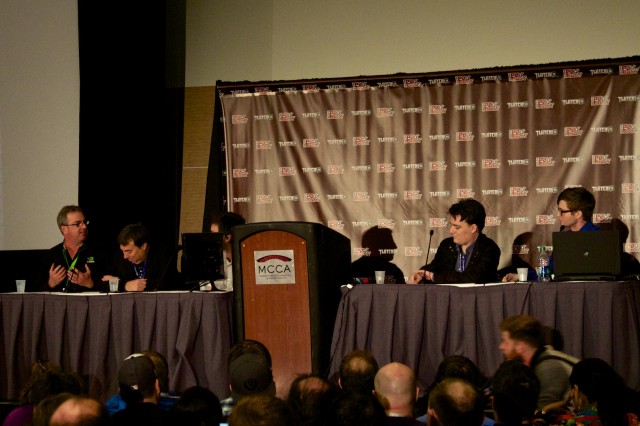 The panel, with Higby's face partially obscured by a monitor.
