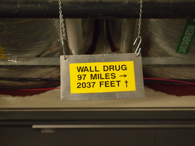 A una milla bajo tierra, un letrero cuelga sobre la puerta del experimento de materia oscura LUX que les dice a los visitantes qué tan lejos está Wall Drug, en ambas dimensiones.