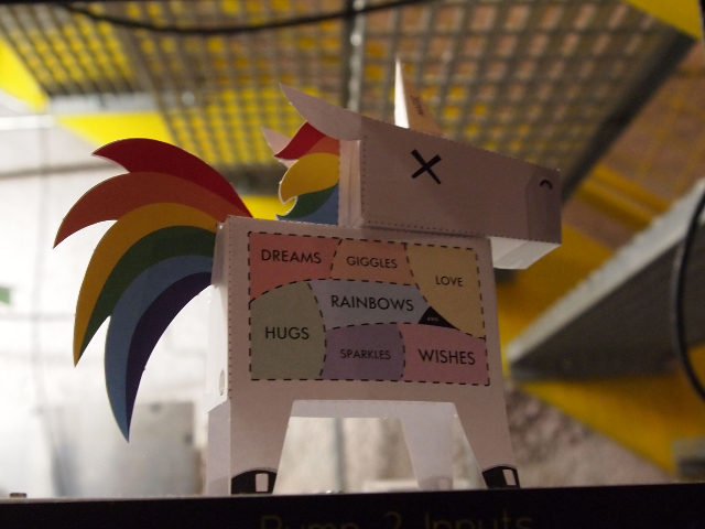 The Lab Housing Lux Has Many Small Paper Unicorns Sitting On Top Of Server Racks And Other Equipment.