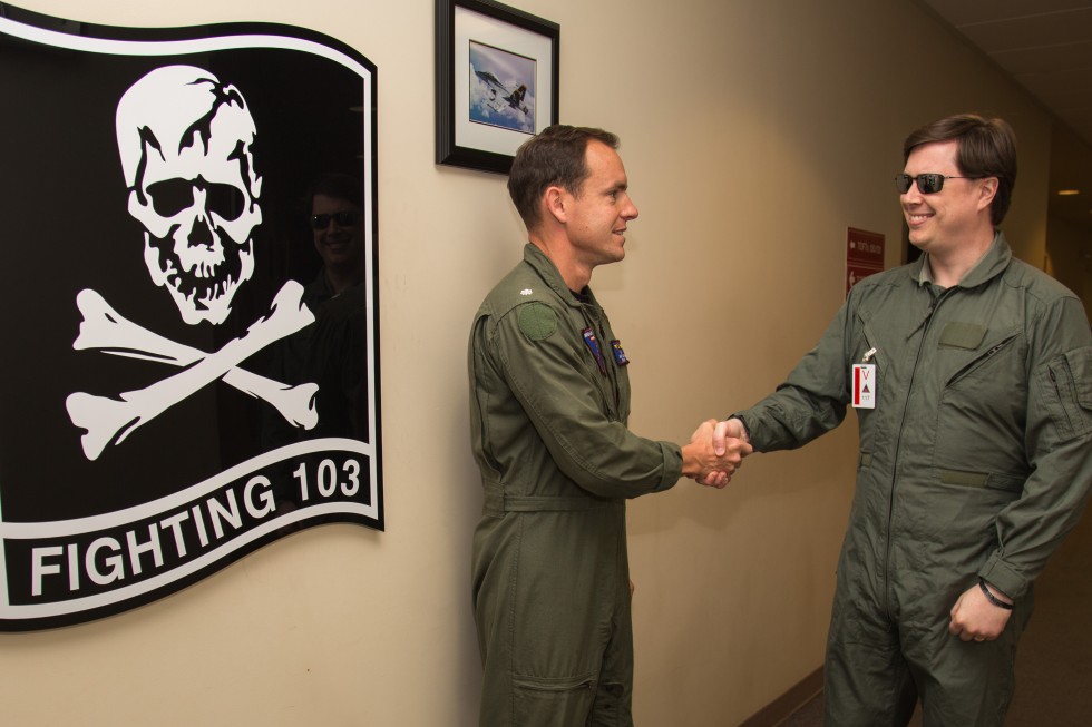 Shaking hands with Commander Matt "Sparky" Smith next to the VFA-103 flag in the sim building.