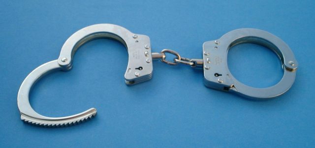 Handcuffs on a nondescript blue background.