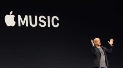 A man speaks on a stage in front of a giant Apple Music logo.