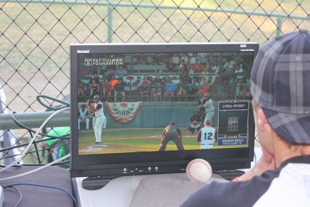 Eric Brynes watches the pitch monitor on a screen from behind home plate.