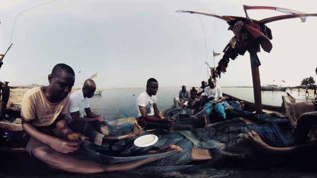 A captured-from-VR shot of the short film <em>Waves of Grace</em>. This exploration of Liberia does little to direct its action, instead dropping a 360-degree camera into various scenes and forcing viewers to manually hunt for visual content around busy scenes.