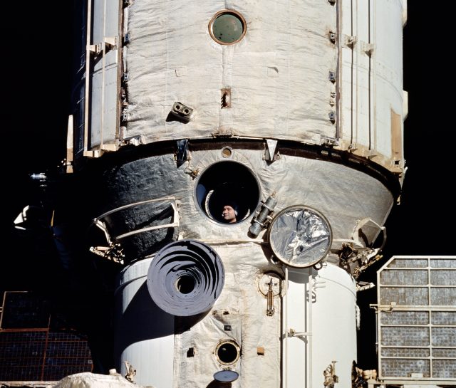 Valery Polyakov looks out of Mir as space shuttle Discovery approaches the space station in 1995.