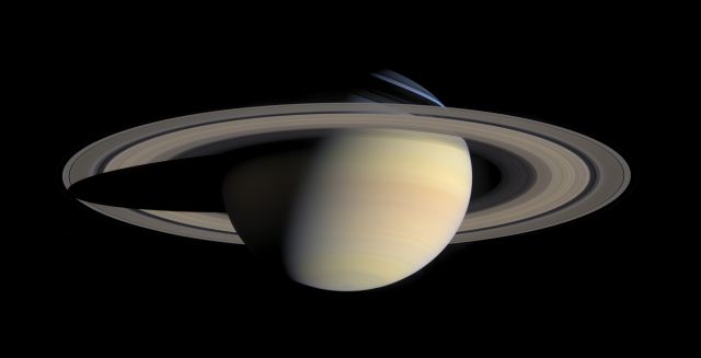 Saturn's moons push and pull on its fluid, making it bulge around the middle.