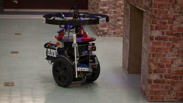 The Unmanned Tactical Autonomous Control and Collaboration (UTACC), a ground robot and small drone team, patrols a simulated town indoors in Ellis Hall at Marine Corps Base Quantico.