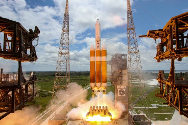 A massive rocket lifts off amidst smoke and flames.