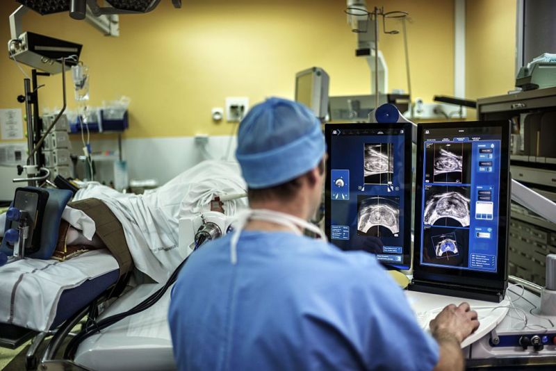 A surgeon performs a robot-assisted prostate tumorectomy using ultrasound imaging.