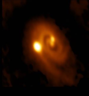 L1448 IRS3B, captured by ALMA. All three protostars are visible within the spiral-shaped disk. C is the brightest and leftmost; -a and -b are close together in the center, with a on the bottom of the pair and slightly to the left. 
