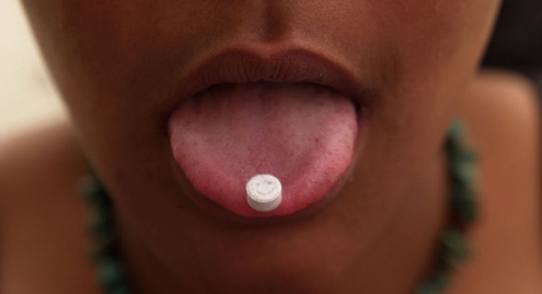 Girl with an ecstasy tablet on her tongue, smiley faced pill, UK 2004 (Photo by Universal Images Group via Getty Images)