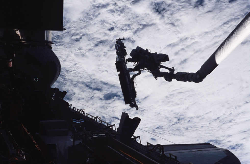 John Grunsfeld, STS-109 payload commander, is anchored on the end of the Space Shuttle Columbia’s robotic arm, moving toward the giant Hubble Space Telescope in 2002.