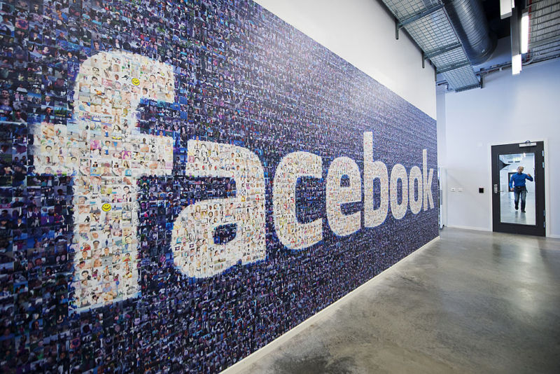 A wall of user photos form a Facebook logo at the company