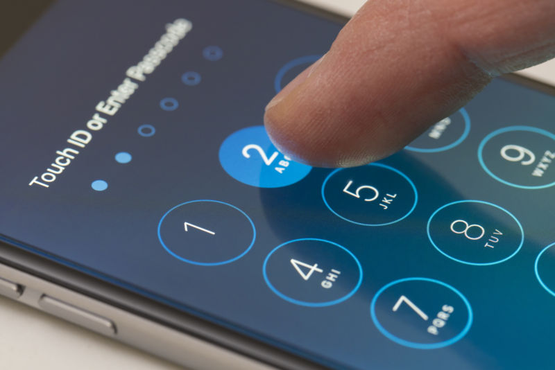 A closeup shot of a finger unlocking an iPhone using a numeric pin.