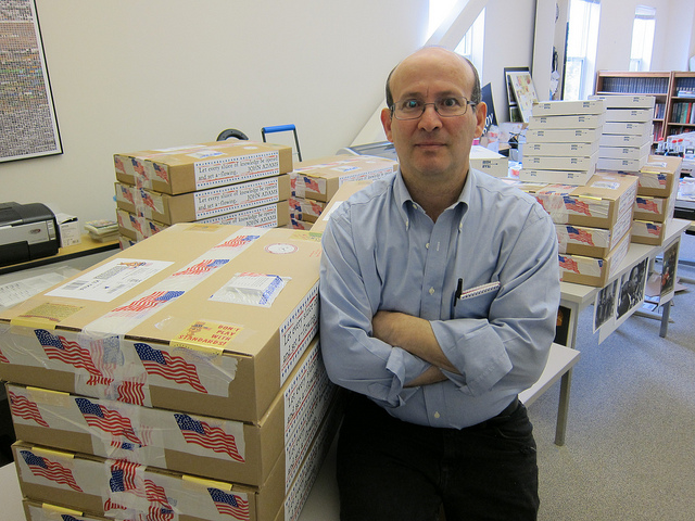 A man stands next to piles of mailing boxes.