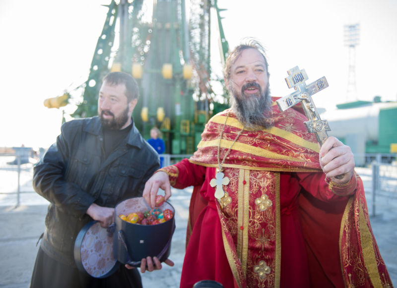 An Orthodox priest hands out Easter eggs to the media at the Baikonur Cosmodrome launch pad after blessing the Soyuz rocket on Wednesday, April 19, 2017 in Kazakhstan. 