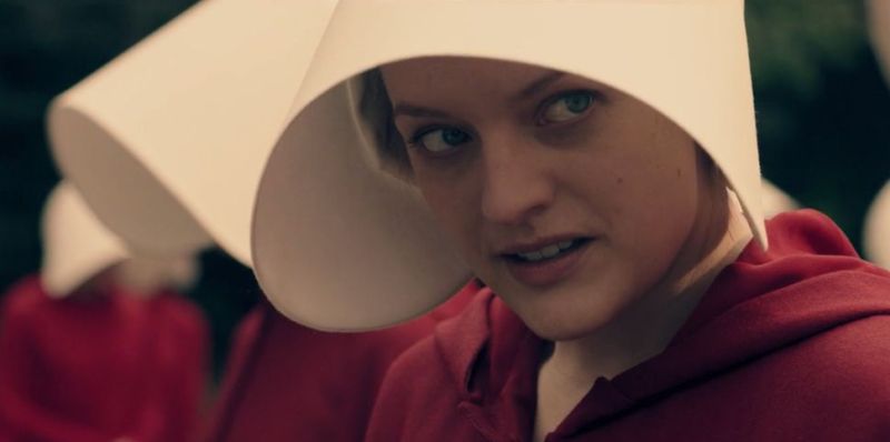 The handmaid June (Elizabeth Moss) must wear regulation red, with a bonnet covering her face, to signify her role as a slave designated to bear children for a prominent man.