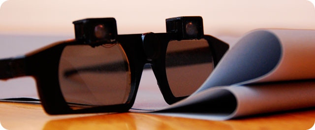 CastAR's first prototype. Subsequent revisions brought the glasses' size down and fidelity up so that its mounted projectors would better convey the feeling that virtual objects appeared on a mat (also known as "augmented reality" or "mixed reality"). However, the project's future is now in doubt.