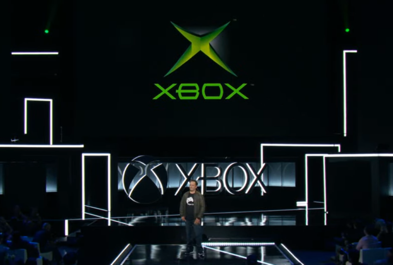 Phil Spencer literally stands next to two Xbox "one" logos.