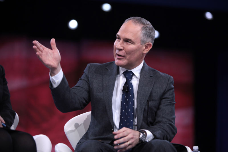 A man in a suit gestures during a presentation.