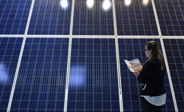 A young woman looks at a photovoltaic installation at a booth at the InterSolar Europe trade fair in the southern German city of Munich on June 1, 2017.