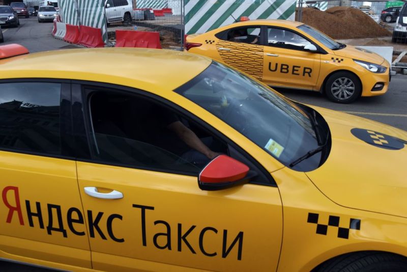 An Uber car (back) and a Yandex.Taxi car drive on a street in Moscow.