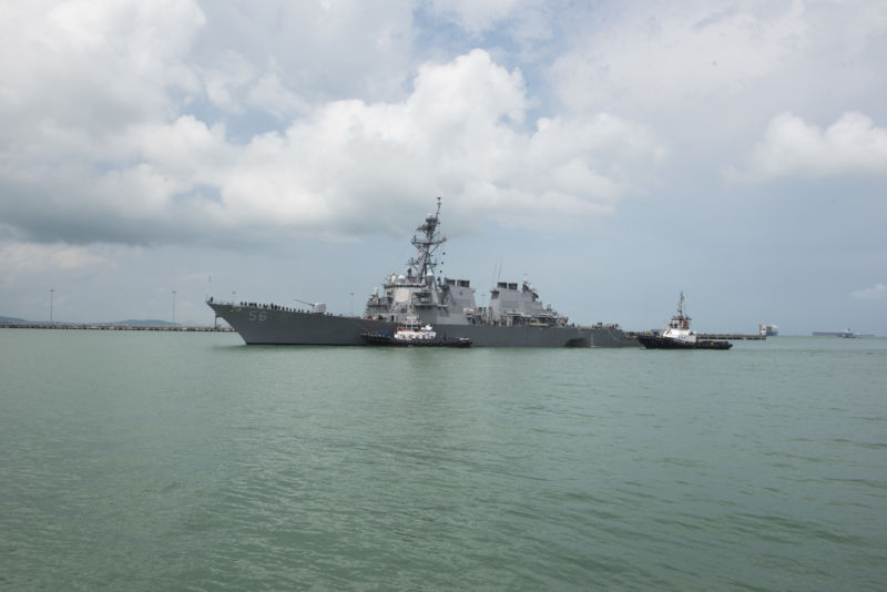 Tugboats from Singapore assist the guided-missile destroyer USS <em>John S. McCain</em> (DDG 56) as it steers toward Changi Naval Base, Republic of Singapore, following a collision with the merchant vessel <em>Alnic MC</em> while underway east of the Straits of Malacca and Singapore on August 21. Ten sailors died in the collision.