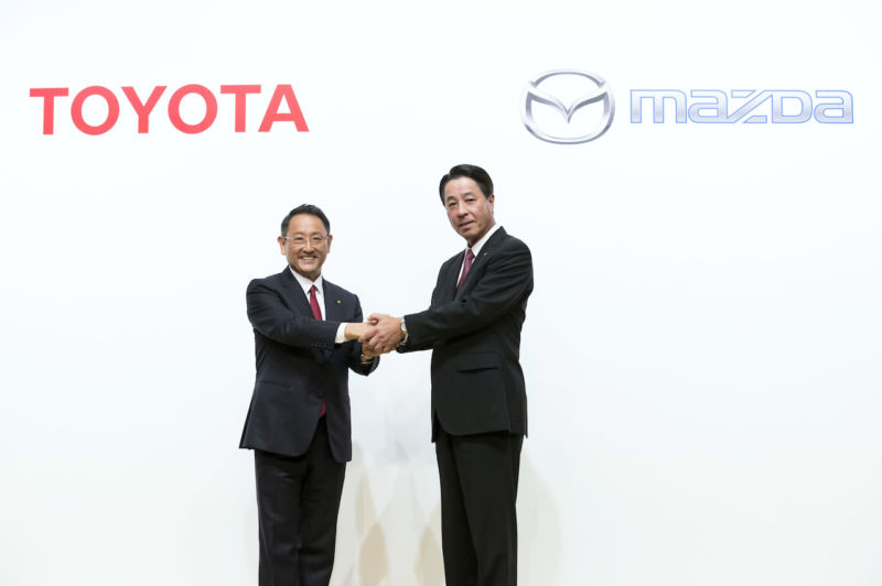 Toyota President Akio Toyoda, left, and Mazda President and CEO Masamichi Kogai, right, shake hands during a photo session at a joint press conference on August 4, 2017 in Tokyo, Japan. 