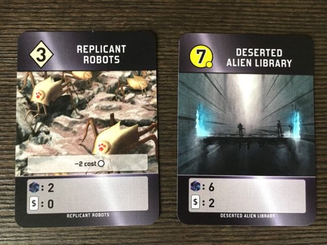 A development (left) and a world (right).  At the bottom of the cards you can see that Replicant Robots produces 2 points and no cards per round, while the (expensive) Deserted Alien Library produces 6 points and 2 cards per round.  The Robots' special ability makes later played worlds cheaper.