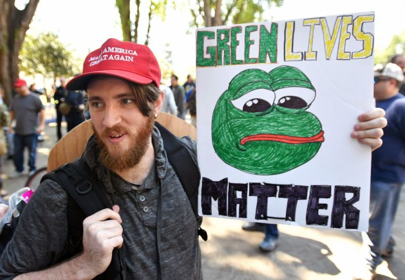 A man holds a sign of Pepe the frog, an alt-right icon, during a rally in Berkeley, California in April 2017. 