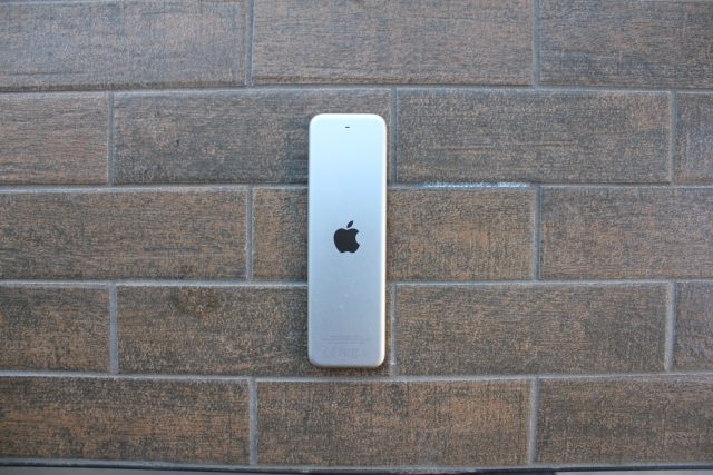 Handheld electronic device against a brick background.