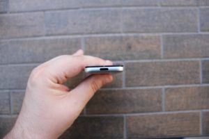 Handheld electronic device against a brick background.