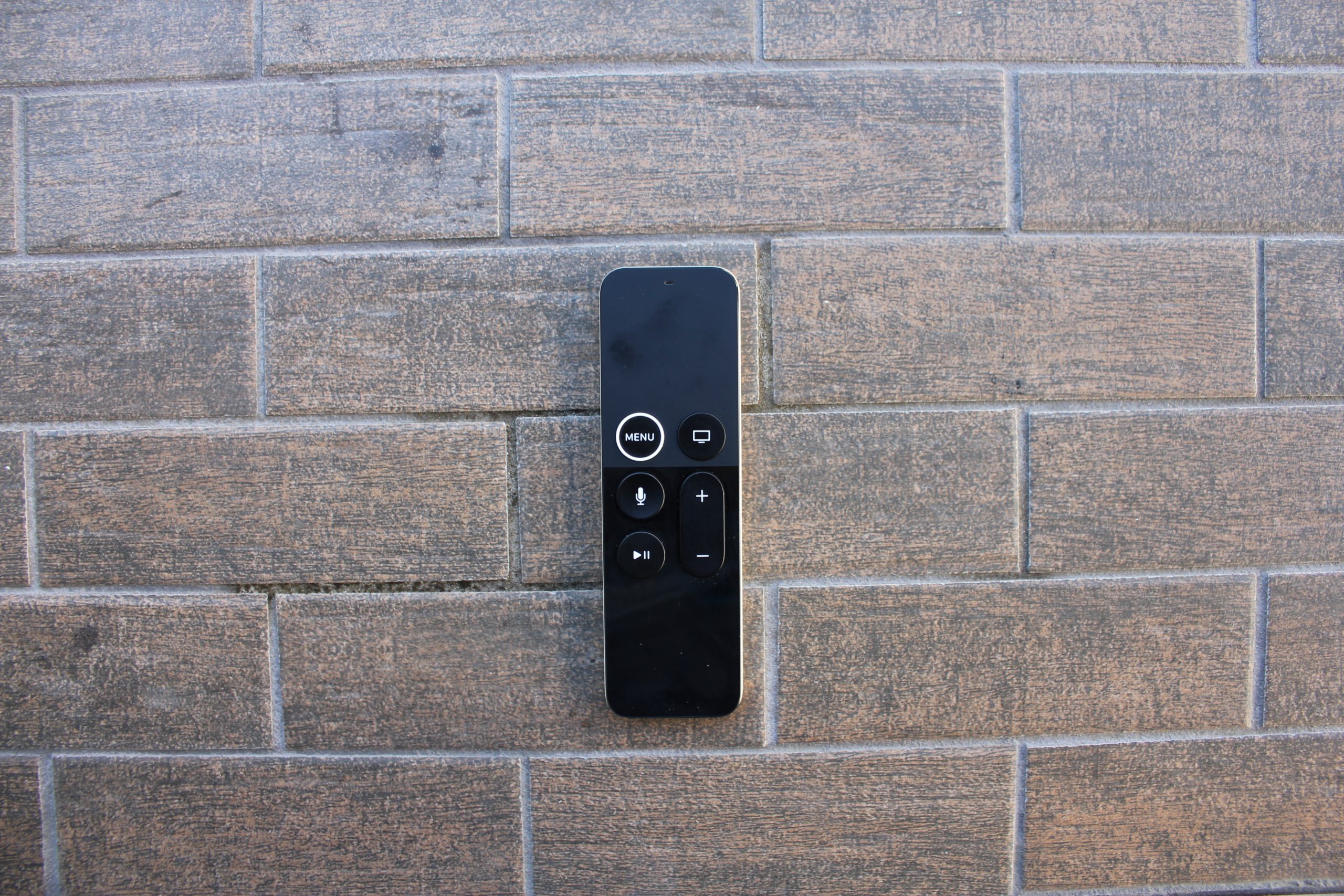 Handheld electronic device against a brick background.