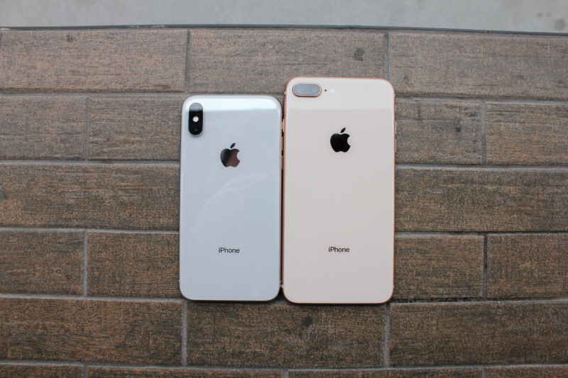 Two smartphones sit side-by-side on a tile surface.