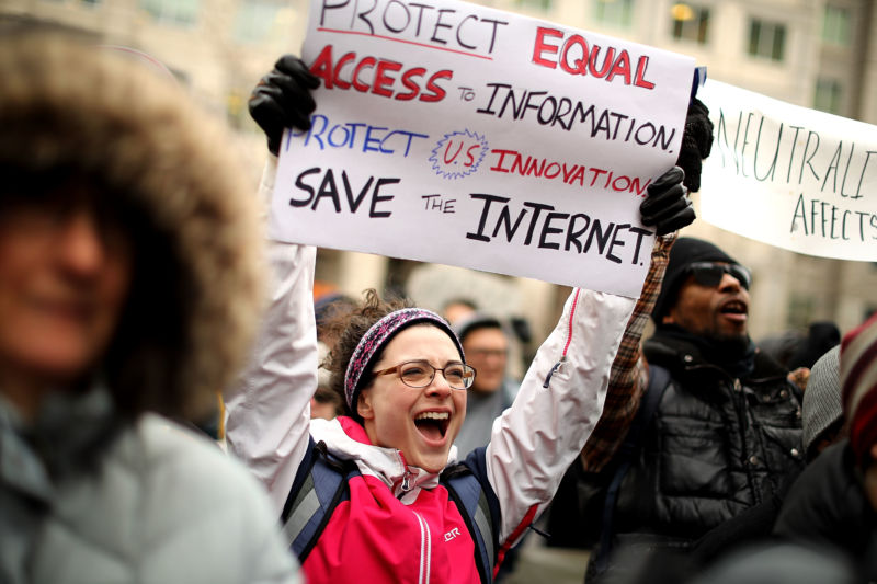 Net neutrality supporters holding signs protesting the FCC's repeal of net neutrality rules.