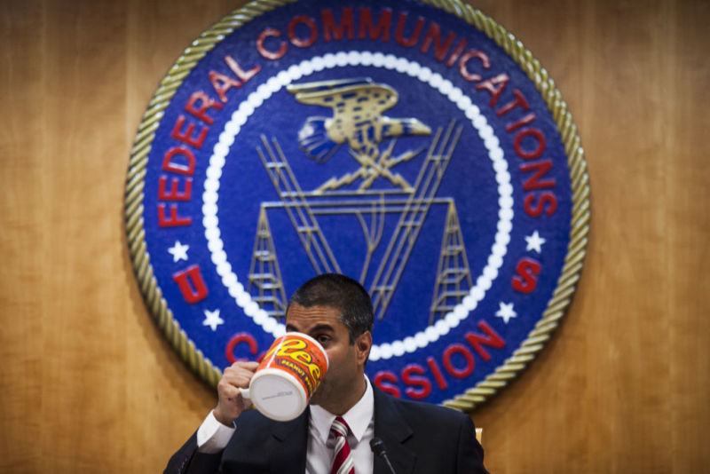 FCC Chairman Ajit Pai drinking from a giant coffee mug in front of an FCC seal.