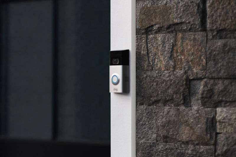 Smart doorbell between a door and a brick wall.